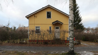 Gable of a small yellow wooden house.