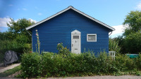 Gable of a small blue wooden house.