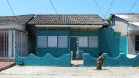 Facade of a small turquoise wooden house.