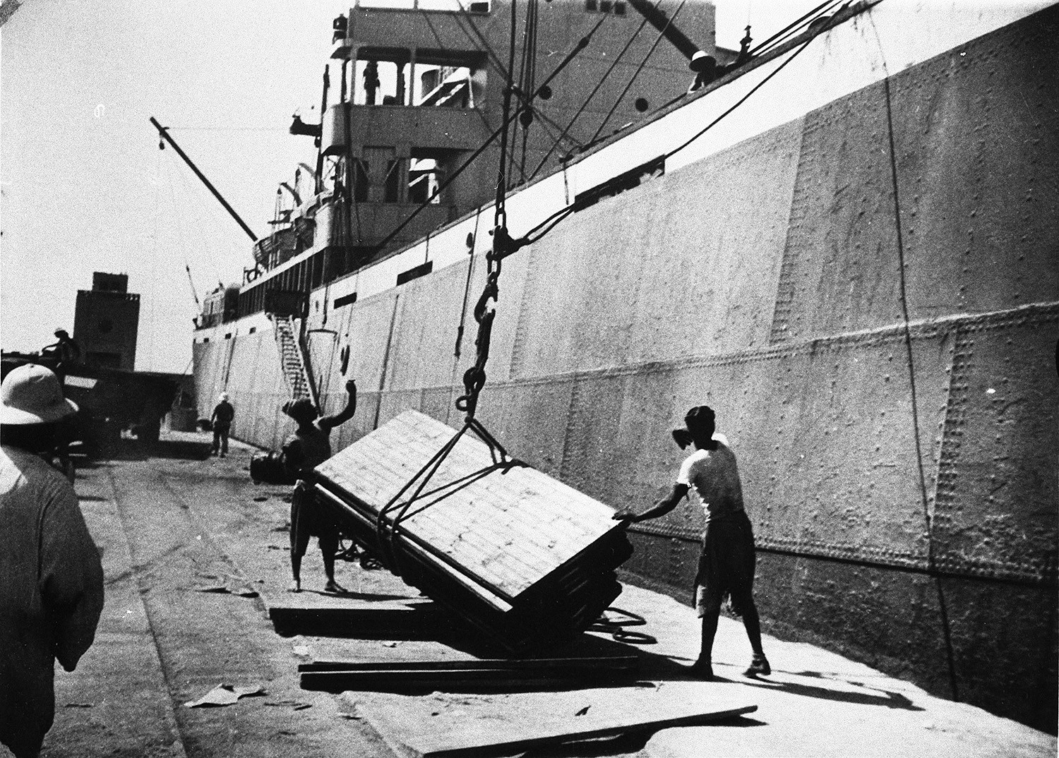 Black and white photo of Puutalo Oy panels being discharged at a harbour. 